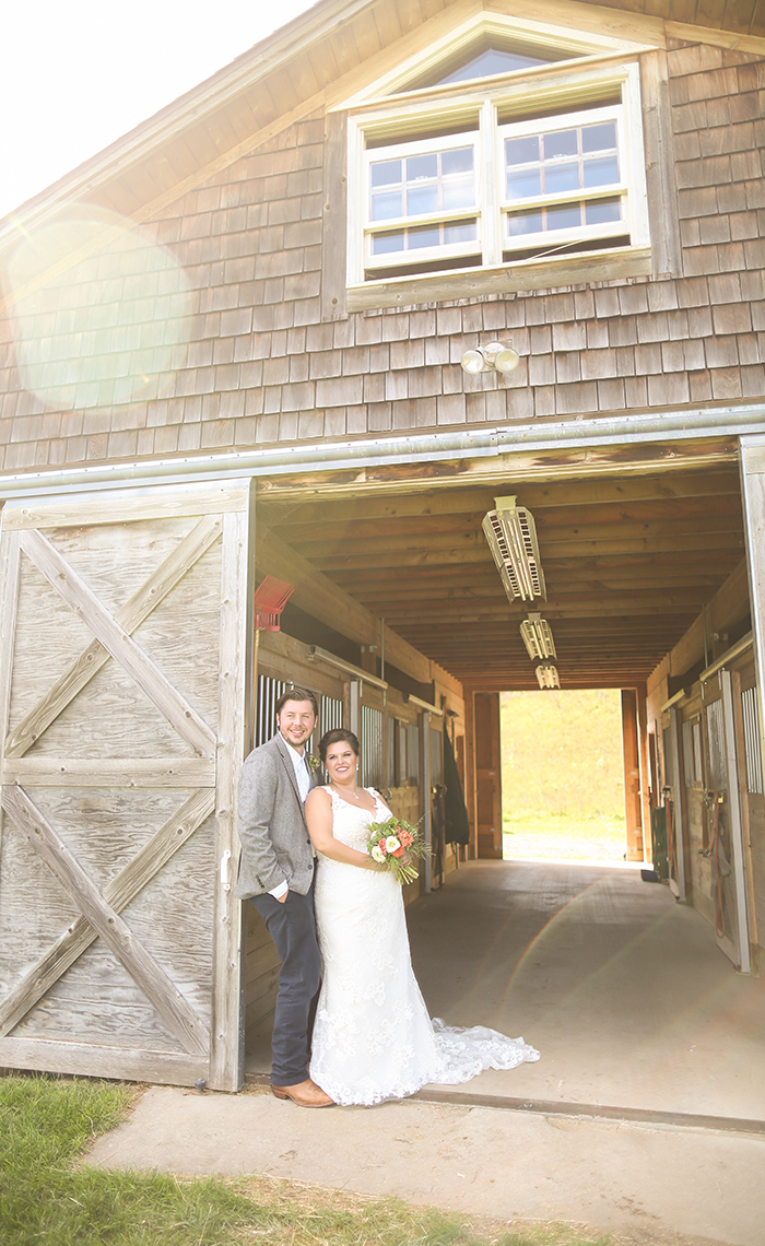 Allison & Nick stand in front of the beautiful working horse barn at the Garvey Family Wedding Barn in Traverse City, Michigan