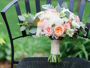 Maureens bridal bouquet, by A Moment in Time, rest on a chair outdoors before their wedding ceremony in Farmington Hills, Michigan.